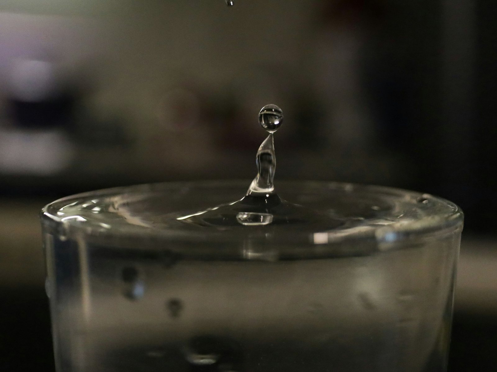 Ein Tropfen fällt in ein Glas Wasser, eingefroren im Aufprallmoment