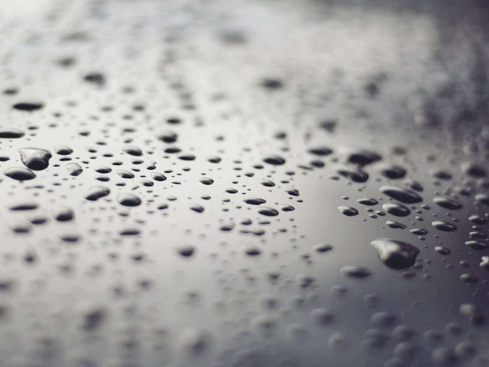 Wassertropfen auf dunklem Glas, Makroaufnahme mit Lichtreflexen